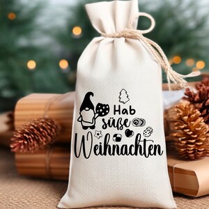 May include: A white fabric gift bag with a black and white illustration of a gnome holding a plate of cookies. The bag has the text "Hab s&uuml;&szlig;e Weihnachten" printed on it.