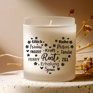 May include: White frosted glass candle with black text that reads "*Gl&uuml;ck. *Tr&auml;ume *Reisen *FREIZEIT. Kraft. *HOBBY Rente. ZIEL *Erholung *Spass *" with small black flower symbols around the text.