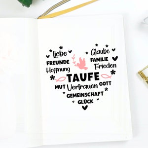 May include: A white notebook with black text that reads "*liebe FREUNDE Hoffnung * Glaube FAMILIE Frieden *TAUFE MUT Vertrauen GOTT GEMEINSCHAFT GL&Uuml;CK * *" with a pink dove and fish graphic.