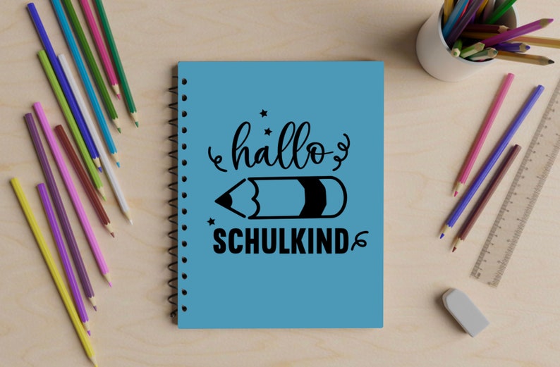 May include: A blue spiral notebook with the text "hallo schulkind" and a black pencil illustration.