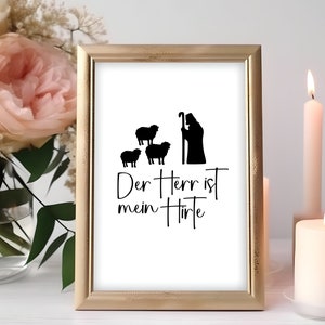 Peut inclure: Une impression encadr&eacute;e avec une silhouette noire et blanche d'un berger avec trois moutons. Le texte "Der Herr ist mein Hirte" est &eacute;crit sous l'image.