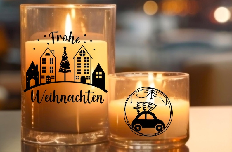 May include: Two glass candle jars with a warm glow. The larger jar has a black and white design of houses and a Christmas tree with the text "Frohe Weihnachten". The smaller jar has a black and white design of a car with a Christmas tree on top, surrounded by a circle.