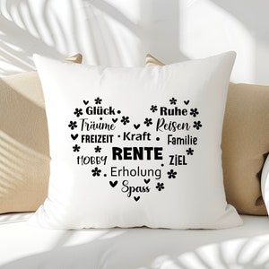 May include: White pillow with black text that reads "Gl&uuml;ck. * Ruhe * *Tr&auml;ume Reisen * FREIZEIT Kraft Familie *HOBBY RENTE ZIEL* *. Erholung * ✓ Spass *" in a heart shape.