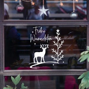 May include: A white vinyl sticker with a Christmas tree, reindeer, and the text "Frohe Weihnachten" on a shop window.