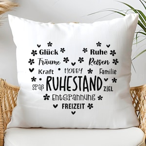 May include: White square throw pillow with a heart-shaped design in black. The design includes the word "RUHESTAND" and other words like "Gl&uuml;ck", "Tr&auml;ume", "Kraft", "HOBBY", "Spa&szlig;", "Entspannung", "Freizeit", "Ruhe", "Reisen", "Familie", and "Ziel".