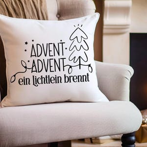 May include: White throw pillow with black text that reads "Advent - Advent ein Lichtlein brennt" and a stylized Christmas tree with lights.