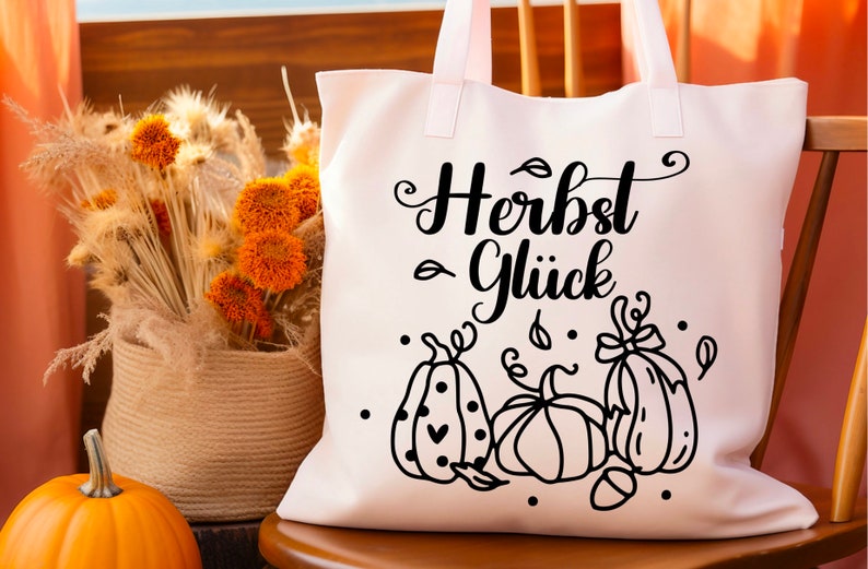 May include: White tote bag with black text that reads "Herbst Gl&uuml;ck" and a black and white illustration of three pumpkins with leaves and dots.