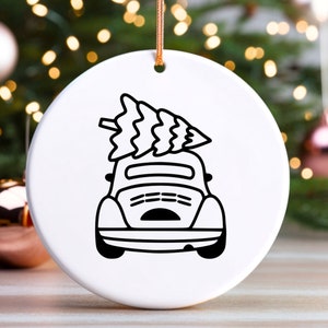 May include: A white ceramic ornament with a black line drawing of a car with a Christmas tree on top.