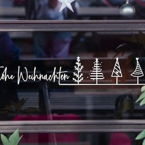 May include: A window with a white sign that says "Frohe Weihnachten" and five stylised Christmas trees.