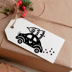 May include: A black and white illustration of a car with a Christmas tree on top. The car is decorated with white dots and a heart. There are stars behind the car.