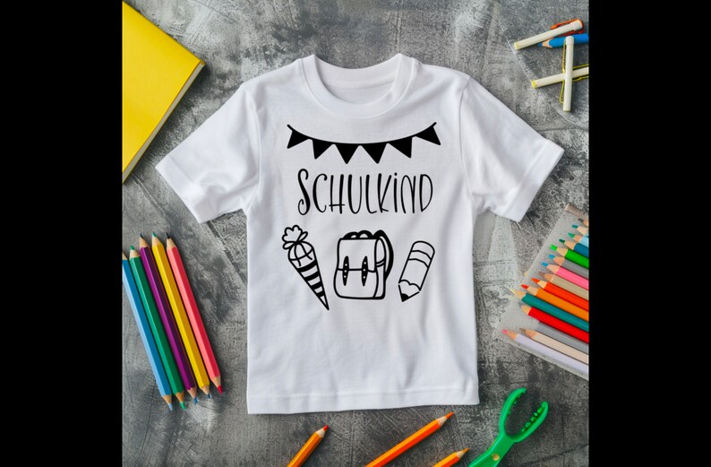 May include: White t-shirt with black text that says "Schulkind" and a black and white illustration of a pencil, backpack, and a cone with a bow on top.