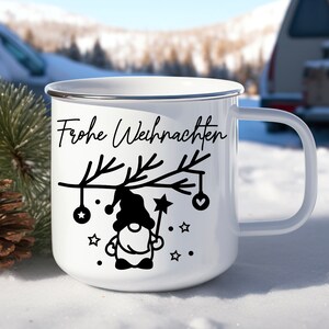 May include: White enamel mug with a black silhouette of a gnome holding a star on a branch with ornaments. The text "Frohe Weihnachten" is printed on the mug.