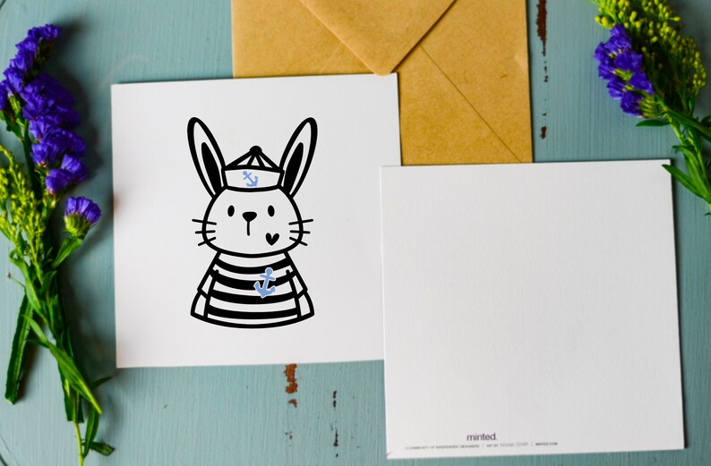 May include: A white card with a black and white illustration of a rabbit wearing a sailor hat with a blue anchor on it. The rabbit is wearing a striped shirt with a blue anchor on it. The card has a white envelope with the word "minted" printed on it.