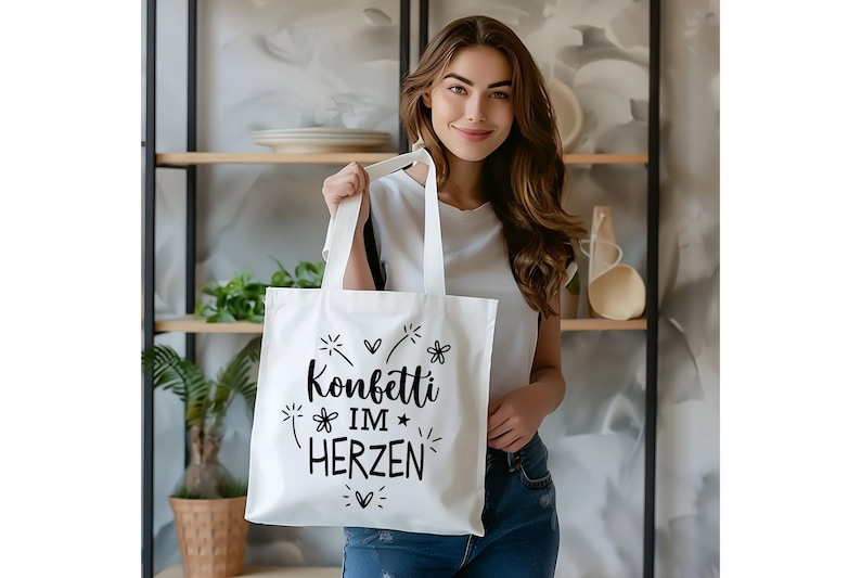 May include: A white tote bag with black text that reads "Konfetti im Herzen" (Confetti in the heart). The bag is being held by a person with long brown hair.