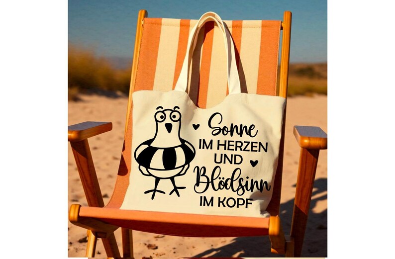 May include: A cream tote bag featuring a cartoon seagull with a life preserver rests on a beach chair. The bag displays the German text "Sonne im Herzen und Bl&ouml;dsinn im Kopf" in black script, with hearts. The chair has orange and white stripes.