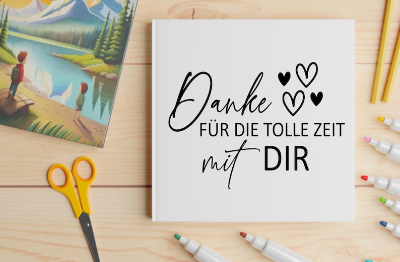 May include: A white card with the German text "Danke f&uuml;r die tolle Zeit mit Dir" in black script, with three heart symbols. The card is on a wooden surface with art supplies and a picture book.