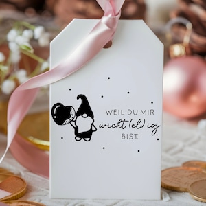 May include: White gift tag with a black and white illustration of a gnome holding a balloon. The tag has black text that reads "Weil du mir wichtig (el) ig bist."