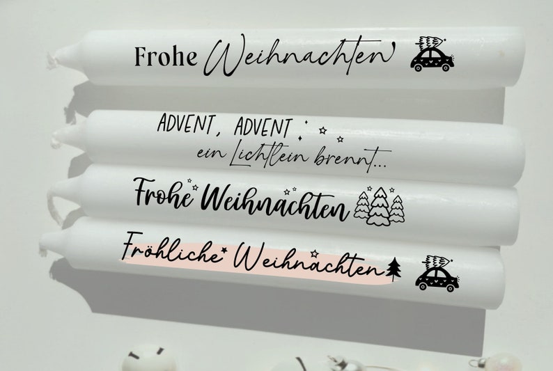 May include: Four white candles with black text and illustrations. The candles have the following text: "Frohe Weihnachten", "ADVENT, ADVENT, ein Lichtlein brennt...", "Frohe Weihnachten", and "Fr&ouml;hliche Weihnachten".