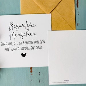 May include: A white card with black text that reads "Besondere Menschen sind die, die garnicht wissen, wie wundervoll sie sind."  There is a small black heart at the bottom of the card.