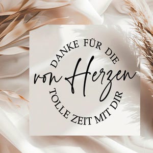 May include: A square card with the German text "DANKE F&Uuml;R DIE von Herzen TOLLE ZEIT MIT DIR" in black script and a circular font. The card is on a white surface with dried plants.