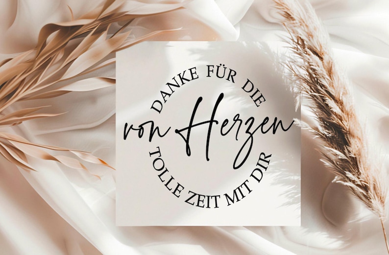 May include: A square card with the German text "DANKE F&Uuml;R DIE von Herzen TOLLE ZEIT MIT DIR" in black script and a circular font. The card is on a white surface with dried plants.