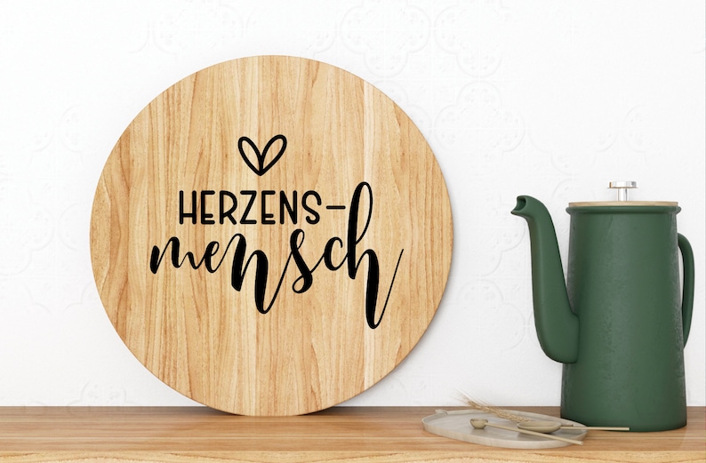 May include: A round wooden sign with the text "HERZENS-mensch" and a small heart symbol.