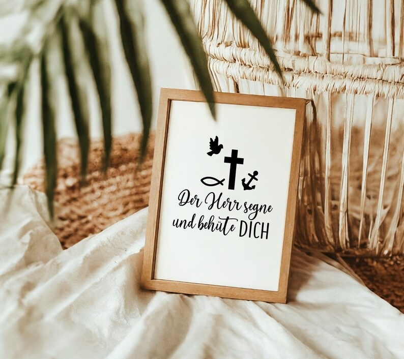 May include: A wooden framed sign with a white background and black text. The text reads "Der Herr segne und beh&uuml;te DICH". There are also black icons of a dove, a fish, a cross, and an anchor.