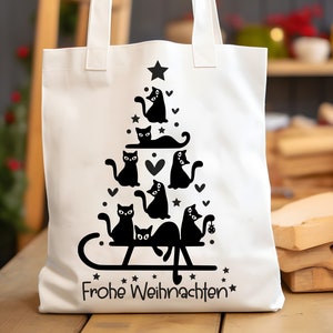 May include: White canvas tote bag with a black silhouette design of a Christmas tree made of cats. The text "Frohe Weihnachten" is printed at the bottom of the bag.