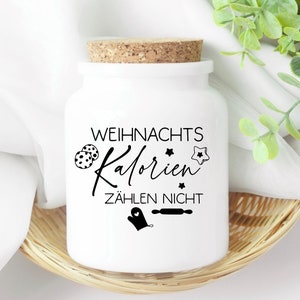 May include: White ceramic jar with a cork lid and a black and white design that says "Weihnachts Kalorien Z&auml;hlen Nicht". The jar is sitting on a woven basket.