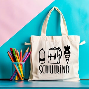 May include: White canvas tote bag with black illustrations of a pencil, backpack, and carrot. The text "SCHULKIND" is printed in black below the illustrations.