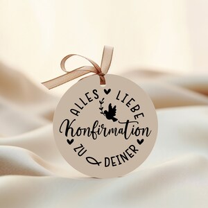 May include: A round, beige tag with a black dove and the text "Alles Liebe Konfirmation zu deiner" in German.