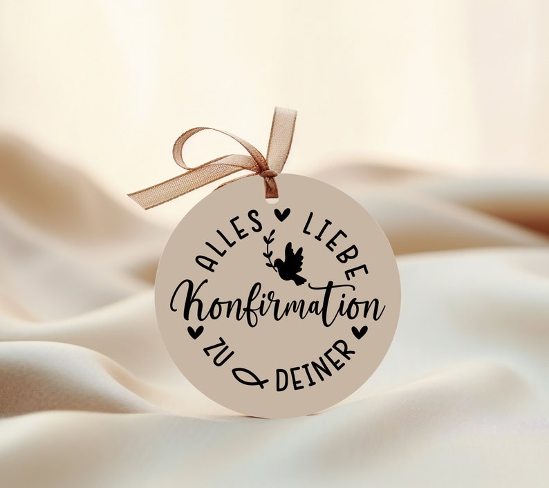 May include: A round, beige tag with a black dove and the text "Alles Liebe Konfirmation zu deiner" in German.