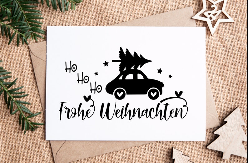 May include: A white card with black text and a black silhouette of a car with a Christmas tree on top. The text says "Ho Ho Ho Frohe Weihnachten".