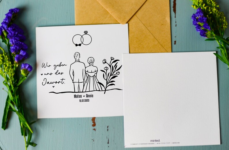May include: A white card with a black line drawing of a couple getting married. The text on the card reads "Wir geben uns das Jawort" and "Mateo & Annie 13.07.2023".