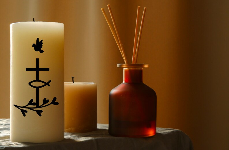 May include: Two white candles, one with a black design of a dove, cross, fish, and branches, and the other plain. A brown glass bottle with wooden sticks for a diffuser.