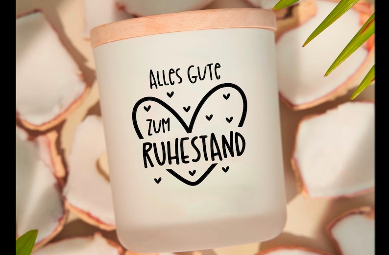 May include: A white candle holder with a wooden lid. The candle holder has the words "Alles Gute zum Ruhestand" in black script inside a heart shape. The background has white and tan decorative pieces.