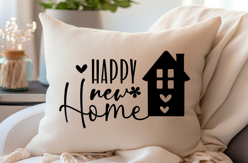 May include: White cushion with black text that reads "Happy new home" and a black silhouette of a house with hearts.