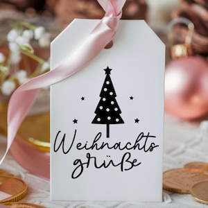 May include: A white gift tag with a black and white illustration of a Christmas tree with stars. The text "Weihnachtsgr&uuml;&szlig;e" is written in black cursive lettering.
