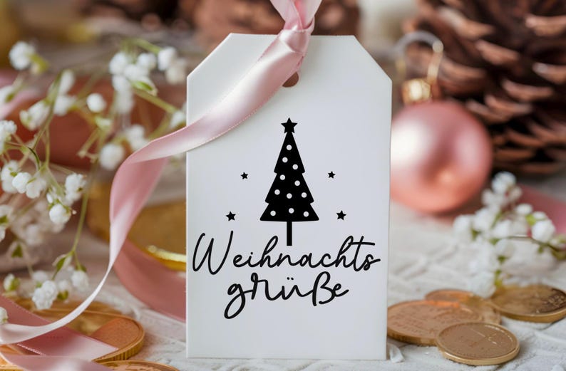 May include: A white gift tag with a black and white illustration of a Christmas tree with stars. The text "Weihnachtsgr&uuml;&szlig;e" is written in black cursive lettering.