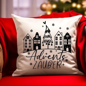Puede incluir: Almohada blanca con una ilustraci&oacute;n en blanco y negro de un &aacute;rbol de Navidad y casas. El texto "Advent's Zauber" est&aacute; impreso debajo de la ilustraci&oacute;n.