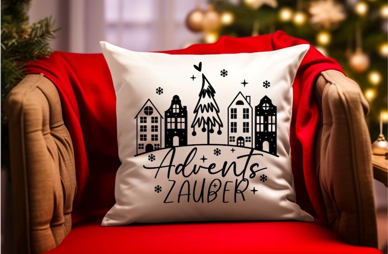 Puede incluir: Almohada blanca con una ilustraci&oacute;n en blanco y negro de un &aacute;rbol de Navidad y casas. El texto "Advent's Zauber" est&aacute; impreso debajo de la ilustraci&oacute;n.