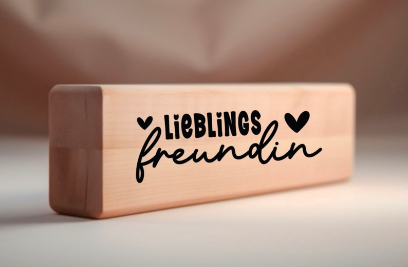 Puede incluir: Un bloque de madera con el texto "LIEBLINGS freundin" y dos peque&ntilde;os corazones a cada lado del texto.