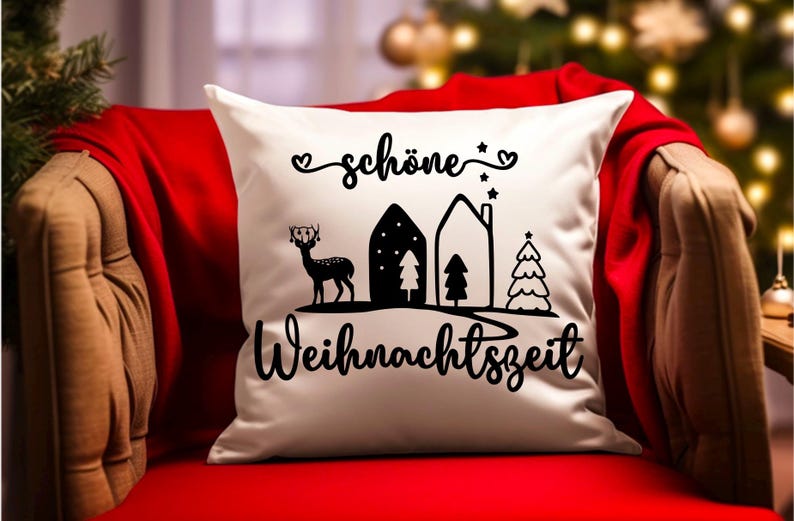 May include: White throw pillow with black text and illustrations. The text reads "sch&ouml;ne Weihnachtszeit" which translates to "beautiful Christmas time". The illustrations include a deer, two houses, and two Christmas trees.