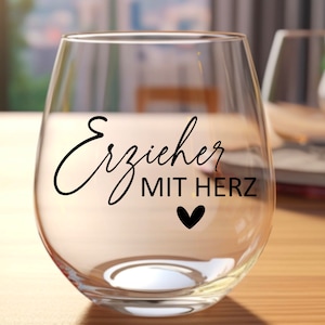 K&ouml;nnte beinhalten: Ein klares Weinglas aus Glas mit dem Text "Erzieher mit Herz" und einem kleinen schwarzen Herz auf der Seite.