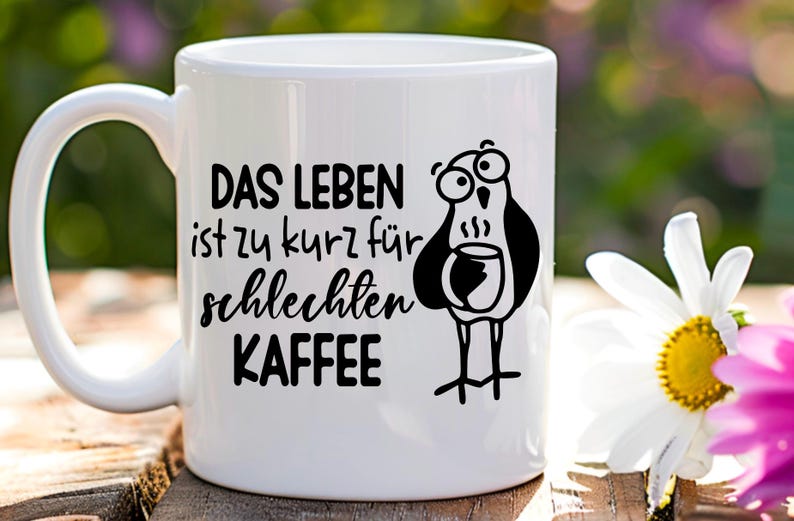 May include: White ceramic coffee mug featuring a black cartoon bird holding a coffee cup. The mug has the German text "DAS LEBEN ist zu kurz f&uuml;r schlechten KAFFEE", which translates to "Life is too short for bad coffee."