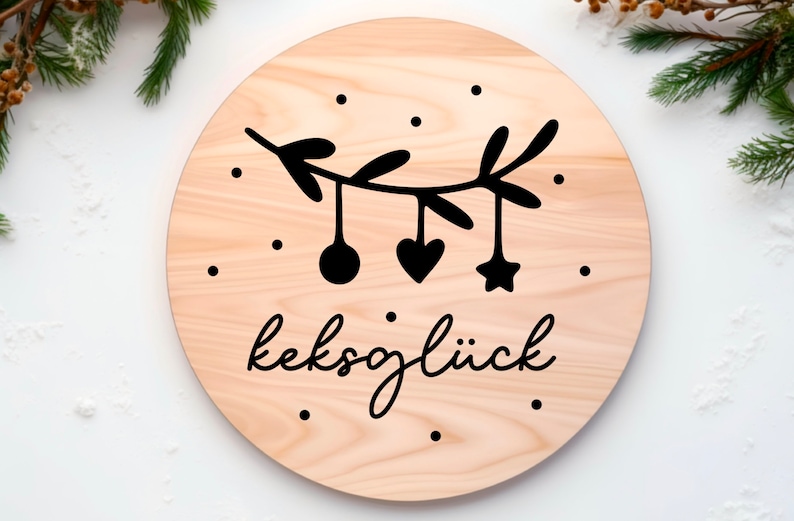 May include: A round wooden sign with a black and white illustration of a branch with ornaments and the text "keksgl&uuml;ck".