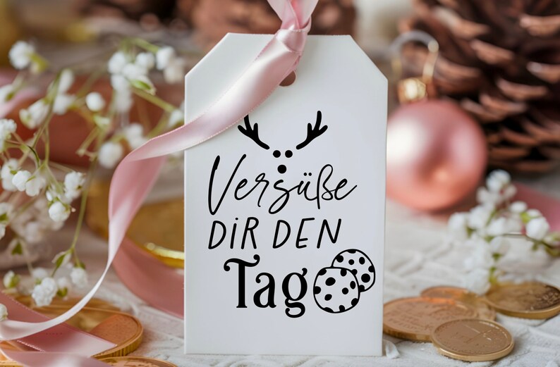 May include: White gift tag with black text and a reindeer illustration. The text reads "Vers&uuml;&szlig;e dir den Tag" which translates to "Sweeten your day".