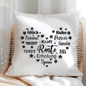 May include: White throw pillow with black text that reads "Gl&uuml;ck. Tr&auml;ume. Reisen. FREIZEIT. Kraft. Familie. HOBBY. Rente. ZIEL. Erholung. Spass." The text is arranged in a heart shape.