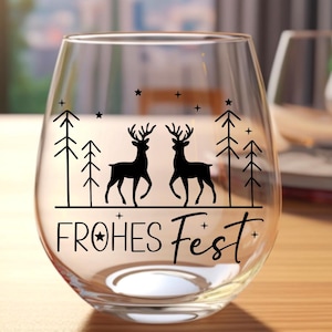 Puede incluir: Una copa de vino de vidrio transparente con un dise&ntilde;o negro de dos ciervos de pie en un bosque con el texto "FROHES FEST" en la parte inferior.
