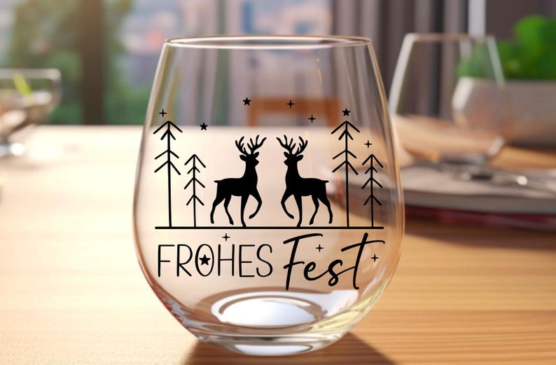 Puede incluir: Una copa de vino de vidrio transparente con un dise&ntilde;o negro de dos ciervos de pie en un bosque con el texto "FROHES FEST" en la parte inferior.